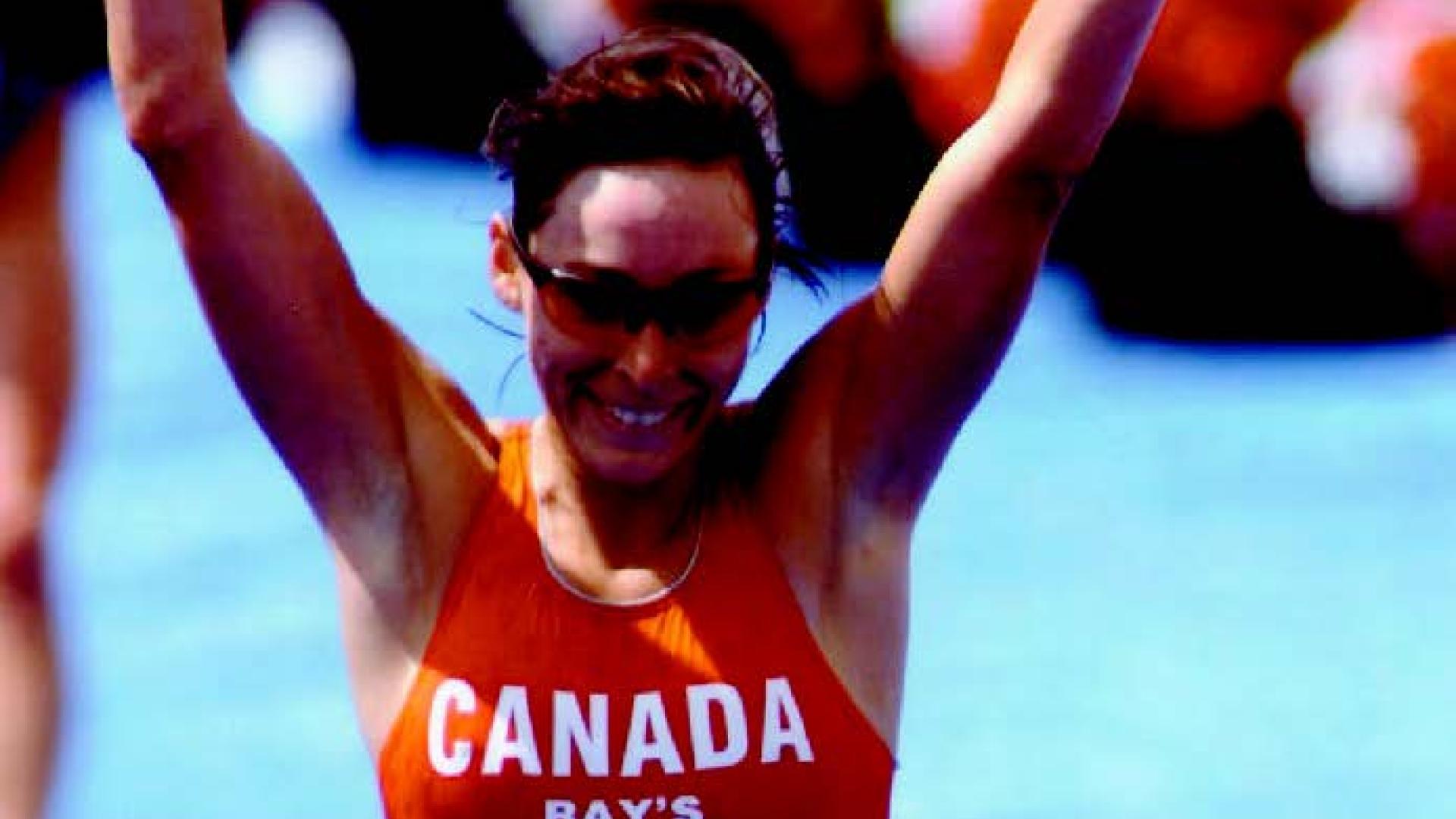 Jill Savege raises her hands as she finishes a race.